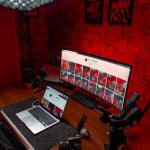 Stylish video editing setup featuring laptop and ultrawide monitor with striking red lighting.